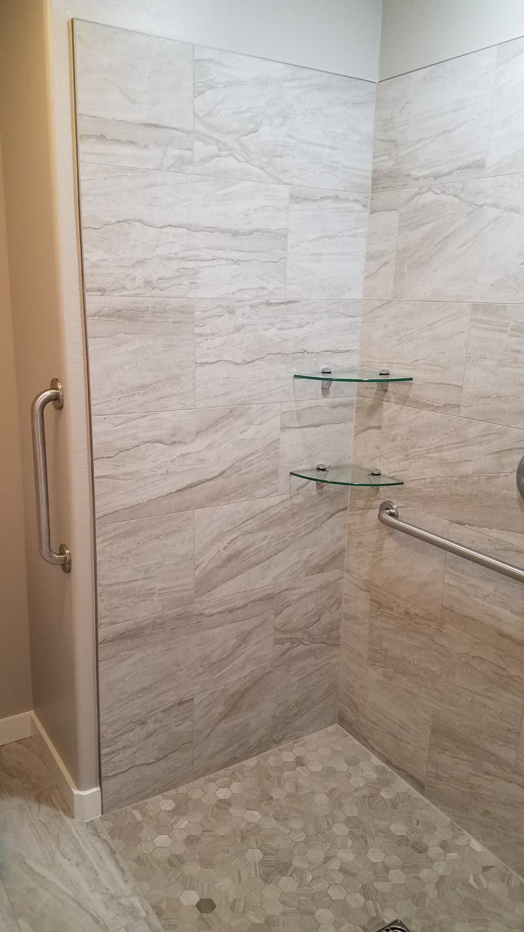 Curbless walk-in shower with large-format tile, grab bars and hexagon floor tile
