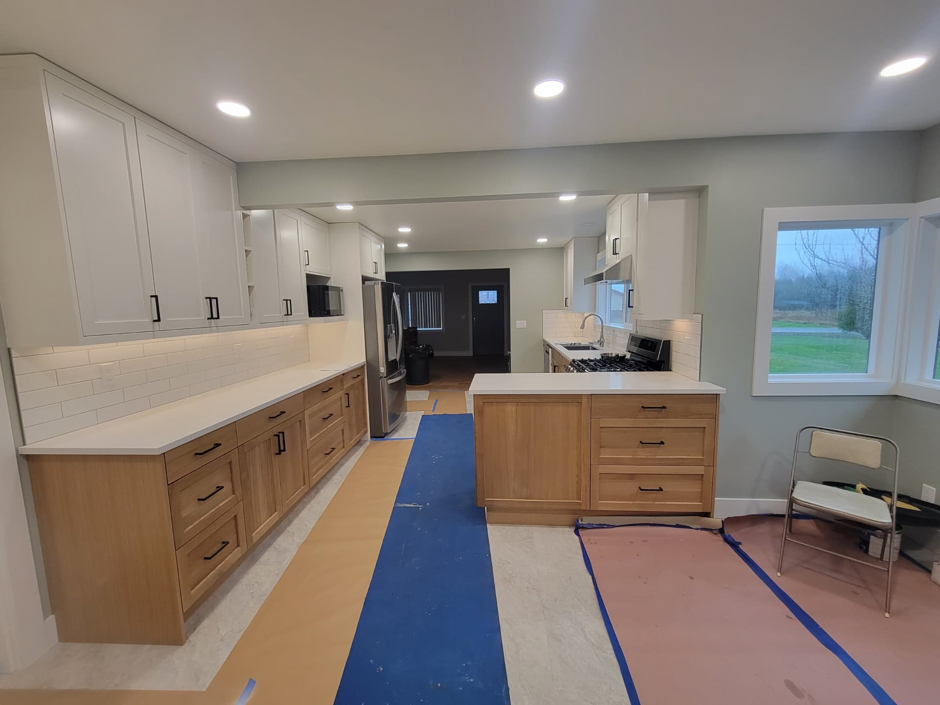 Open-concept kitchen remodel with white uppers, oak base cabinets and peninsula seating