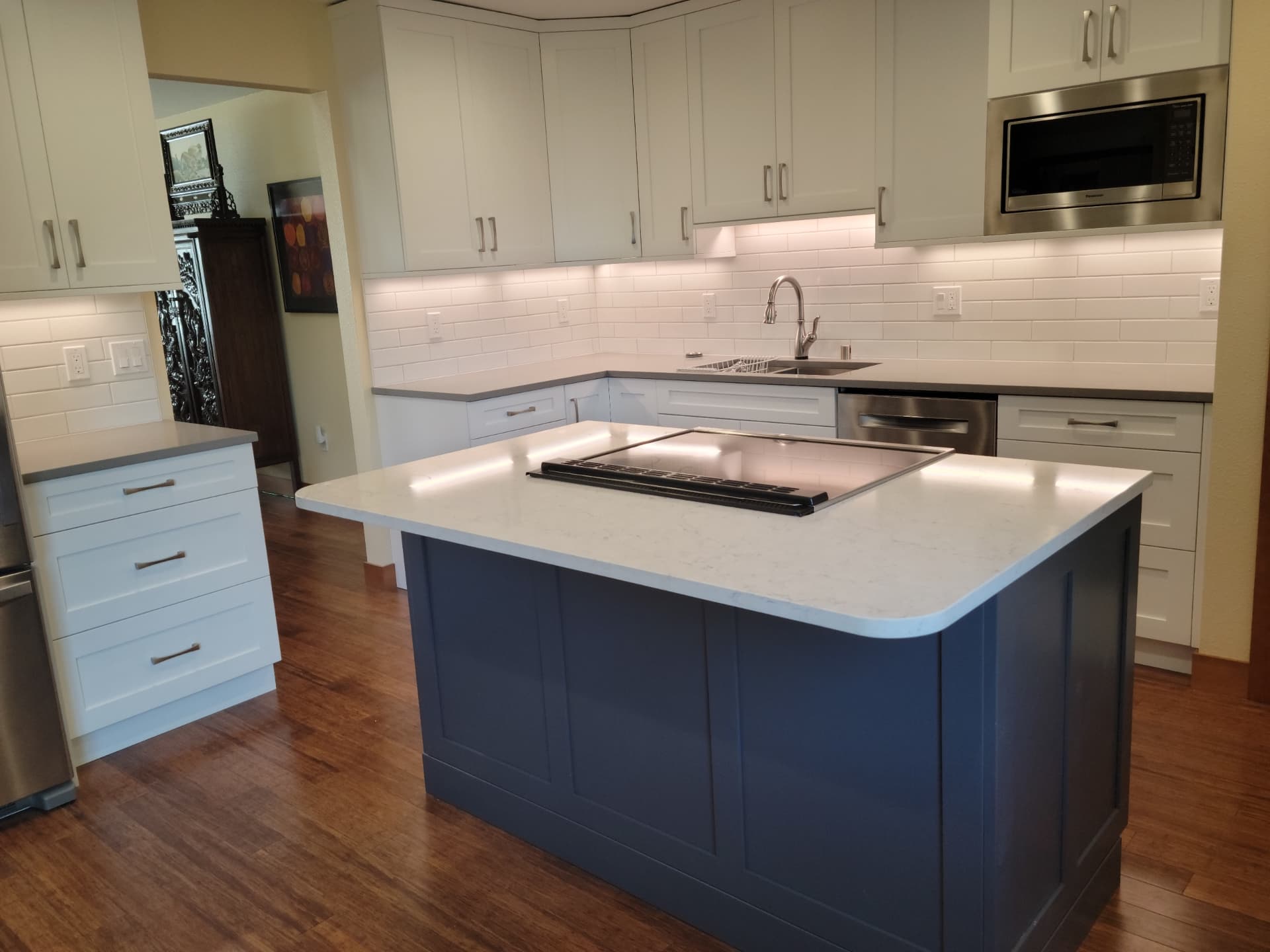 Two-tone kitchen remodel with white perimeter cabinets and a blue island cooktop