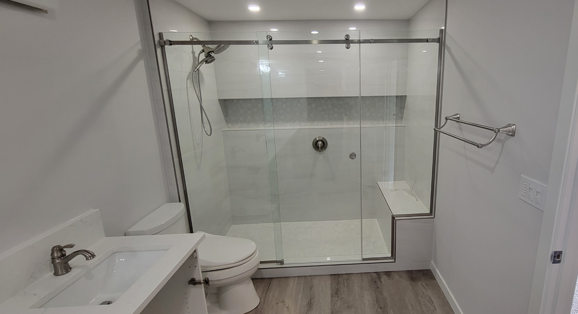 Sliding glass door shower with white tile, mosaic niche and built-in bench