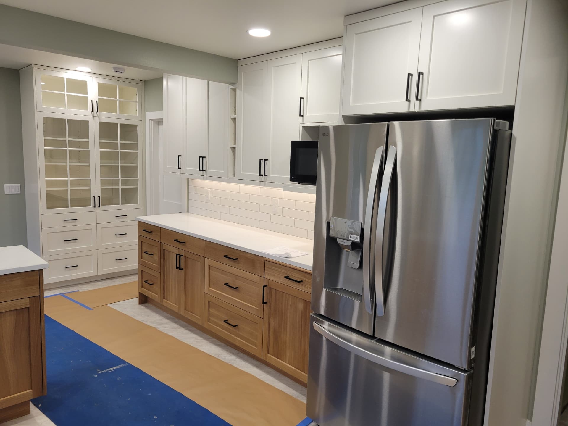 Custom pantry cabinetry and glass-front hutch in a finished kitchen remodel