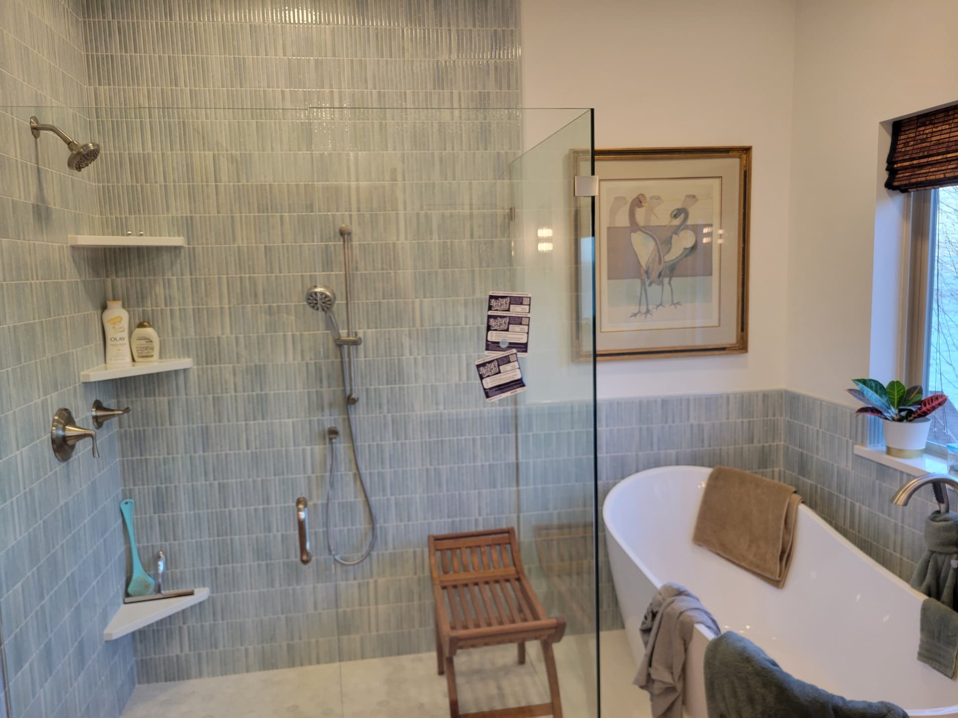 Blue-green tiled walk-in shower with frameless glass, teak bench and freestanding tub